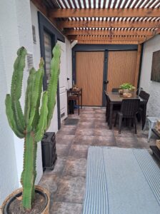 Comedor exterior bajo pérgola de madera en el patio de la casa en Quilicura