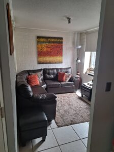 Living con sofás de cuero y alfombra, casa en venta en Quilicura