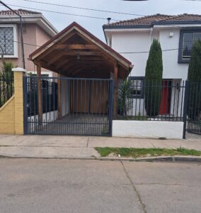Fachada de la casa de dos pisos en venta en Quilicura, con portón y pérgola de entrada